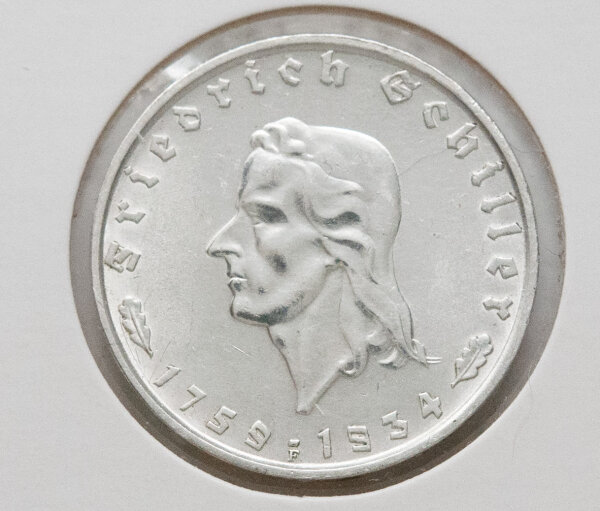 Die Rückseite der Münze zeigt den deutschen Reichsadler in einer klaren, hoheitlichen Darstellung. Über dem Adler ist im Halbkreis „Deutsches Reich“ zu lesen, während darunter der Nennwert „2 Reichsmark“ in eleganter Frakturschrift aufgebracht ist. Flankiert wird der Text von kleinen Eichenblättern, die das klassische Design abrunden.