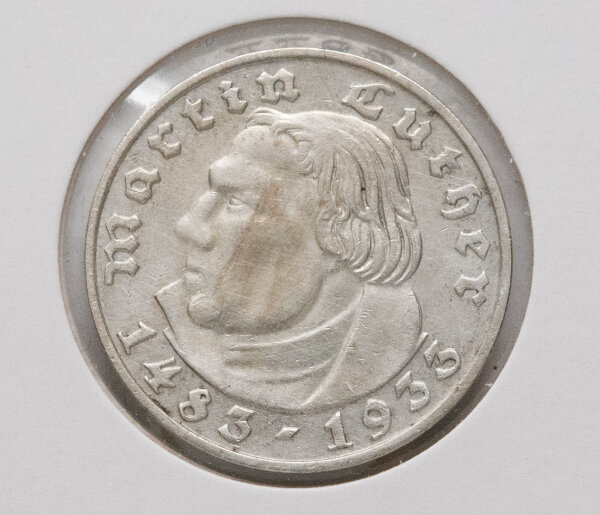 Die Rückseite zeigt den deutschen Reichsadler in klassischer Gestaltung. Die Umschrift „Deutsches Reich“ und der Nennwert „2 Reichsmark“ in Frakturschrift umrahmen das Motiv. Zwischen den Worten befinden sich dezente Eichenblätter. Unter dem Adler ist deutlich das Münzzeichen „D“ für München zu erkennen.