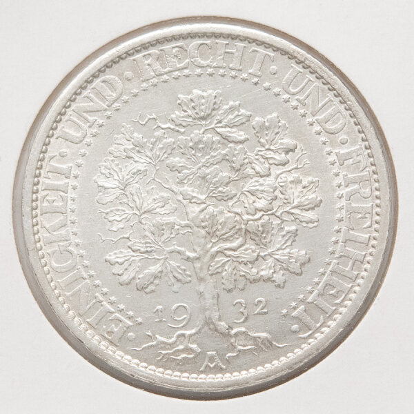 Die Detailaufnahme zeigt die Rückseite der 5 Reichsmark Silbermünze von 1932 mit dem charakteristischen, tief verwurzelten Eichbaum-Motiv. Unter den Wurzeln ist der Prägebuchstabe A für Berlin sowie das Prägejahr 1932 zu erkennen. Der Rand trägt die Inschrift EINIGKEIT UND RECHT UND FREIHEIT, unterbrochen von kleinen Sternen.