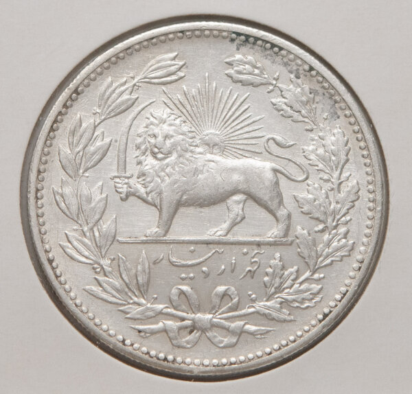 Vorderseite der persischen 5-Kran-Münze: Darstellung des schwerttragenden Löwen vor der aufgehenden Sonne (Shir-o-Khorshid). Umgeben von einem Kranz, am unteren Rand die Wertangabe in persischer Schrift. Die Münze zeigt eine attraktive historische Patina.