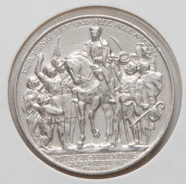 Vorderseite der 2-Mark-Gedenkmünze 1913: Darstellung des Königs Friedrich Wilhelm III. zu Pferd vor jubelnder Menge. Die Inschrift „DER KÖNIG RIEF UND ALLE ALLE KAMEN“ ist am Rand scharf ausgeprägt. Die Münze zeigt einen hellen Silberglanz.