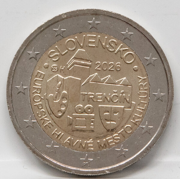 Nahaufnahme der Motivseite der 2-Euro-Münze Trenčín 2026. Zu sehen ist die Burg Trenčín über einer Anordnung von Kunstsymbolen (Palette, Kamera, Masken). Der bankfrische Glanz der UNC-Prägung ist deutlich erkennbar.